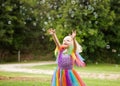 A little girl in a bright costume chasing bubbles