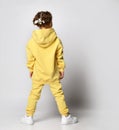 Little girl in a bright yellow sports suit stands with her back to the camera. Royalty Free Stock Photo