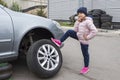 Little girl and a broken car outdoors. Auto repair concept