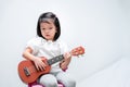 Little girl with brown ukulele toy gift. Child learn to play strum instruments