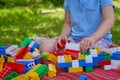 A child plays with colored cubes in the yard,a little girl builds a house from construction blocks in the summer Royalty Free Stock Photo