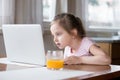 Little girl busy playing computer in kitchen at home Royalty Free Stock Photo