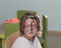 little girl with butterfly painted face sitting inside the room