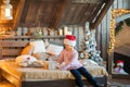 Little girl in the cap of Santa Claus is waiting for the New Year on the bed. Girl on Christmas with gifts in the bedroom in the s Royalty Free Stock Photo