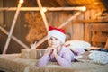 Little girl in the cap of Santa Claus is waiting for the New Year on the bed. Girl on Christmas with gifts in the bedroom in the s Royalty Free Stock Photo