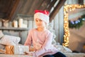 Little girl in the cap of Santa Claus is waiting for the New Year on the bed. Girl on Christmas with gifts in the bedroom in the s Royalty Free Stock Photo