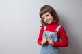 A little girl in a car mechanic uniform is holding wrenches