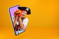 Little girl in a carnival costume of a pirate on Halloween looks from a smartphone. Royalty Free Stock Photo