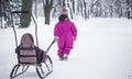 Little girl carries a sled in the Park, an independent child