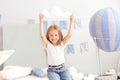 A little girl in casual clothes holds a cloud pillow against the background of a decorative balloon. The child plays in the childr Royalty Free Stock Photo