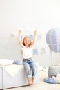 A little girl in casual clothes holds a cloud pillow against the background of a decorative balloon. The child plays in the childr Royalty Free Stock Photo