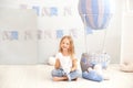 A little girl in casual clothes holds a cloud pillow against the background of a decorative balloon. The child plays in the childr Royalty Free Stock Photo