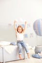 A little girl in casual clothes holds a cloud pillow against the background of a decorative balloon. The child plays in the childr Royalty Free Stock Photo