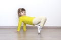 Little girl in casual yellow clothes doing gymnastics at home