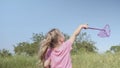 Little girl catches soap bubbles in butterfly net while playing in tall grass in park. Cute little girl smiles and catches on soap Royalty Free Stock Photo