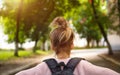 A little girl of Caucasian in a school uniform with a backpack looks at the road in the school yard.