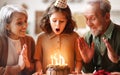 Little girl celebrating birthday while her loving senior grandparents at home Royalty Free Stock Photo