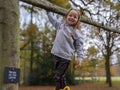 Little girl cheeky smile climbs tree with sign saying please do not climb Royalty Free Stock Photo