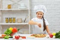 Little girl in chef hat and an apron cooking pizza Royalty Free Stock Photo