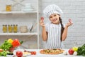 Little girl in chef hat and an apron cooking pizza Royalty Free Stock Photo