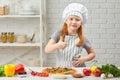 Little girl in chef hat and an apron cooking pizza