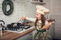 Little girl in a chef`s hat helps in the kitchen with cooking Royalty Free Stock Photo