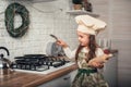 Little girl in a chef`s hat helps in the kitchen with cooking Royalty Free Stock Photo