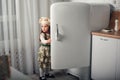 Little girl in a chef hat looks into the refrigerator Royalty Free Stock Photo