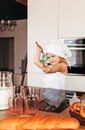 A little girl in a chef`s hat plays with kitchen appliances in the kitchen Royalty Free Stock Photo