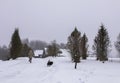 Little girl child in a beige coat running with small balck dog on snow covered field in the village Royalty Free Stock Photo