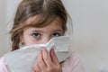 Little girl child blows snot out of nose into paper handkerchief during a cold