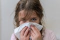 Little girl child blows snot out of nose into paper handkerchief during a cold