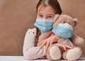 Little girl child holding a teddy bear wearing a mask. Concept of health care and virus protection covid Royalty Free Stock Photo