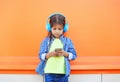 Little girl child listens to music in headphones and using smartphone