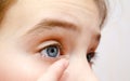 Little girl child putting contact lens into her eye closeup