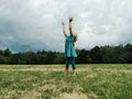 Little girl child stand on meadow with hands up to the sky in hope. Freedom, innocence and adolescense concept. Loneliness and Royalty Free Stock Photo