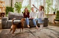 Little girl, child teaching dog commands with her parents. Family spending time together at home in living room Royalty Free Stock Photo