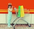 Little girl child with trolley cart and shopping bags on city street Royalty Free Stock Photo