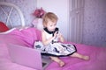 Little girl child using a laptop sitting on a bed Royalty Free Stock Photo