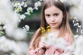 Little girl child in a white flower garden, holding a tiny bunch of yellow flowers in her hands and looking at the camera Royalty Free Stock Photo