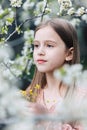 Little girl child in a white flower garden, holds a tiny bunch of yellow flowers in her hands Royalty Free Stock Photo