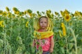 Little girl in a children`s mask of a beekeeper among a sunflower
