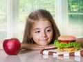 Little girl choose between apple and hamburger.Unhealthy nutriti