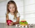 Little girl choose between apple and hamburger.Unhealthy nutriti