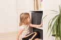 Little girl chooses a book in a bookcase at home. Royalty Free Stock Photo