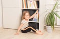 Little girl chooses a book in a bookcase at home. Royalty Free Stock Photo