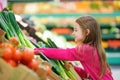 Little girl choosing fresh leek in a food store Royalty Free Stock Photo