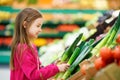 Little girl choosing fresh leek in a food store