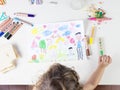 Little girl choosing a green coloured pencil in a wood table for Royalty Free Stock Photo