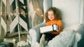 Little girl with a Christmas gift sitting in a comfortable chair Royalty Free Stock Photo